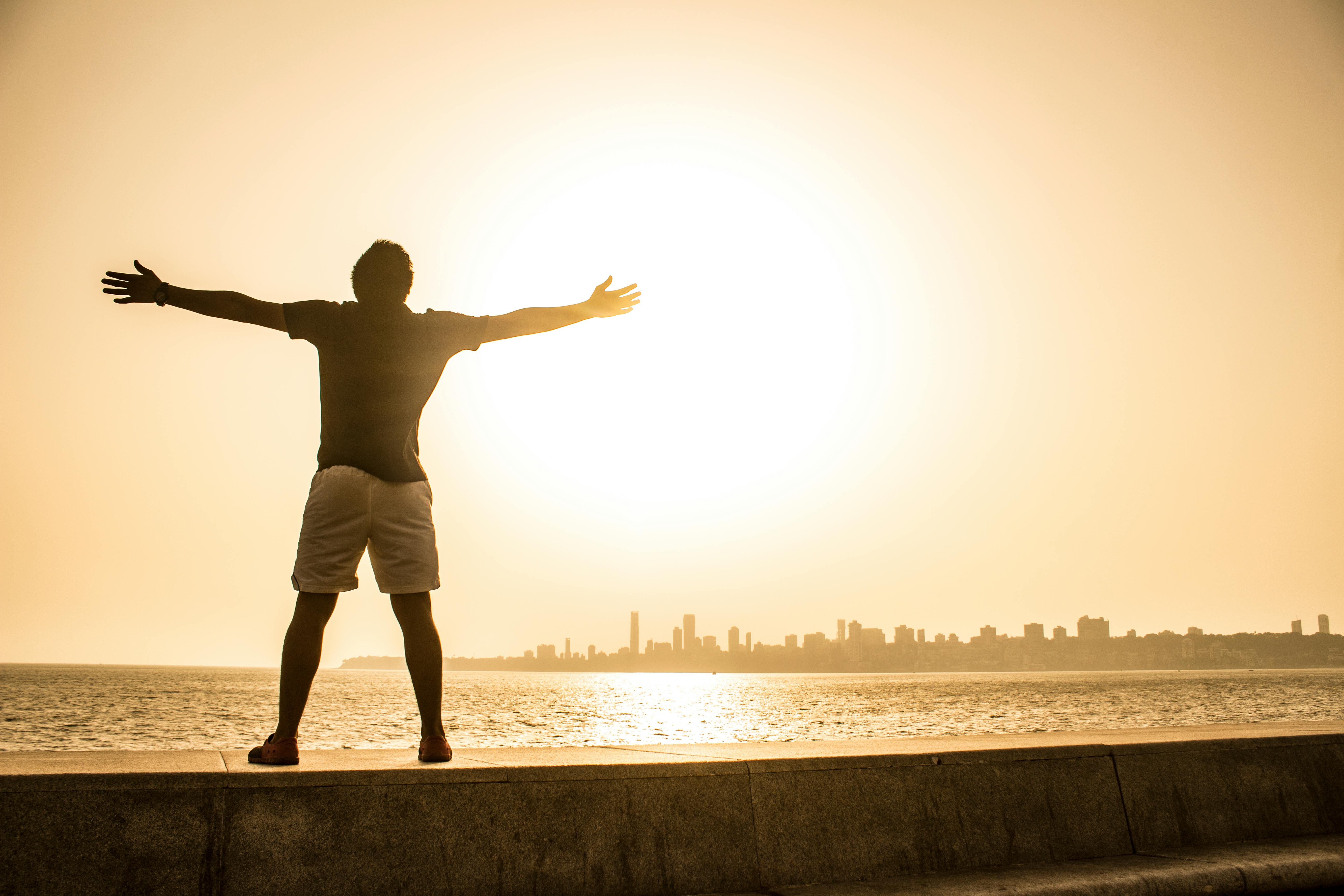 Man extended arms by the sea